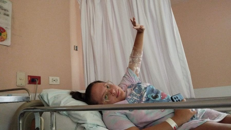 A child recovering in a hospital bed, waving after treatment through Healing Horizons