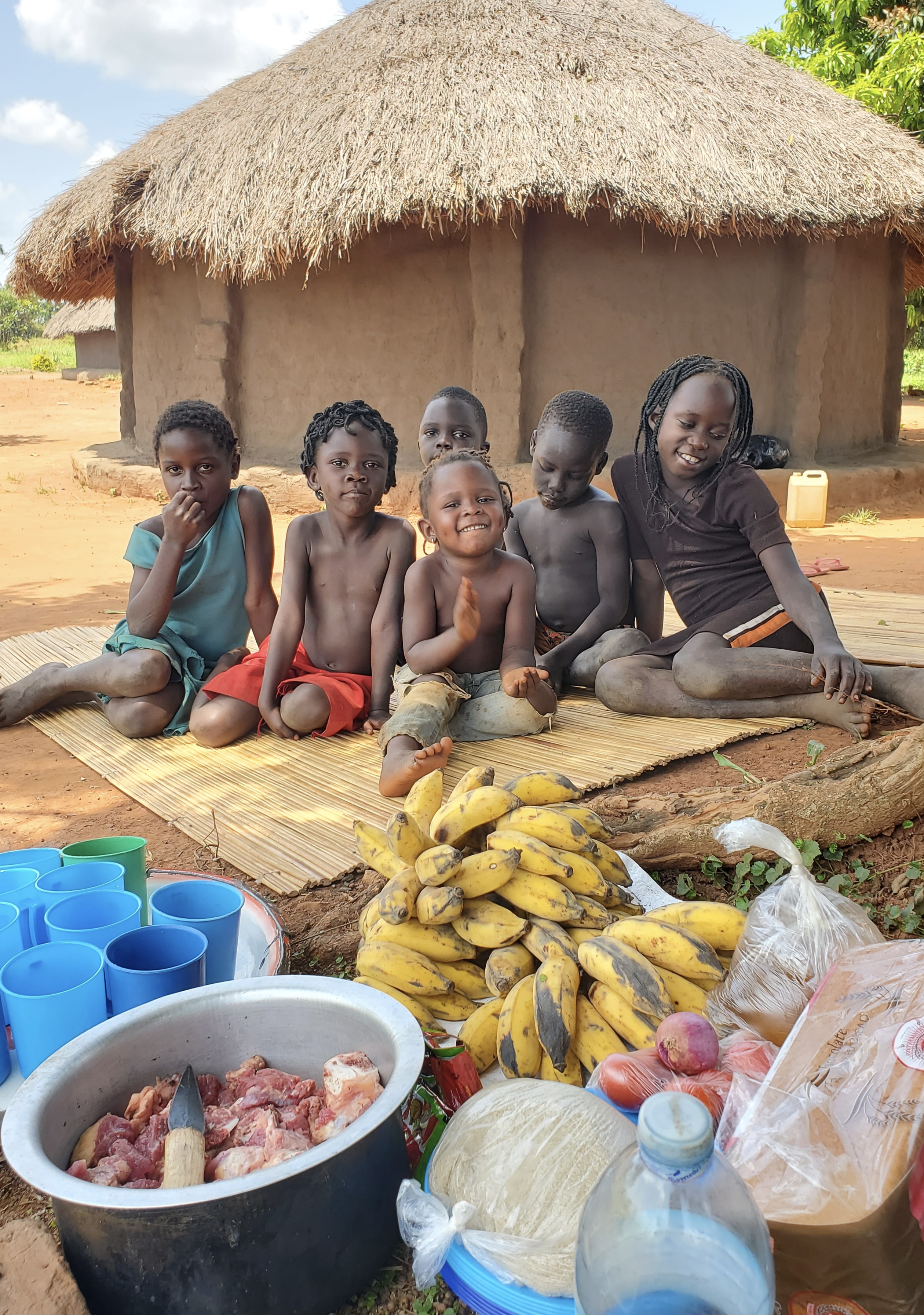 Children in Bwobo Village, Uganda with food supplies prepared for a shared meal